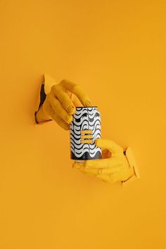 two hands holding a coffee cup on top of a banana peel and an orange background