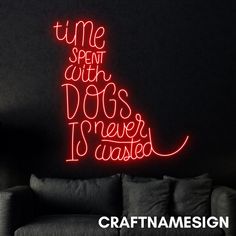 a neon sign that says time spent with dogs never wasted on the wall next to a couch