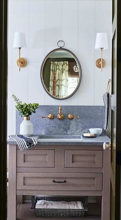 a bathroom sink with a mirror above it and two lamps on the wall next to it