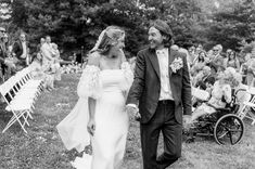 black and white photo of bride and groom walking hand in hand at outdoor wedding ceremony