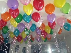 many balloons with streamers hanging from the ceiling