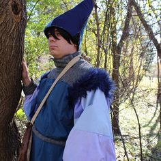 a woman dressed in costume standing next to a tree