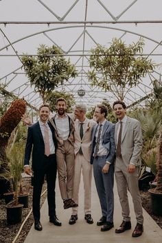 Groomsmen pose for photo in tonal neutral suits surrounded by plants Groomsmen Attire Mix And Match, Mixed Groomsmen Attire, Non Matching Groomsmen Attire, Groomsmen Casual Wedding, Different Color Suits Groomsmen, Multicolor Groomsmen Attire, Groomsmen Attire Multicolor, Mismatched Suits Wedding, Mismatched Wedding Party Groomsmen