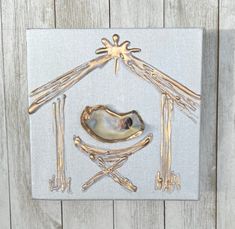 a nativity scene made out of metal and wood on a white canvas with gold accents