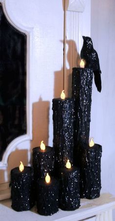 a bunch of candles that are sitting on a mantle in front of a mirror with a bird on it