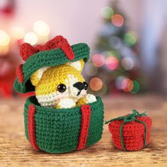 a small crocheted dog in a green and red bag with a christmas tree behind it