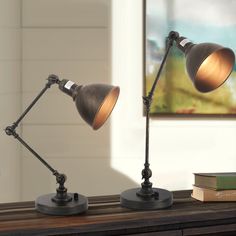 two desk lamps sitting on top of a wooden table next to a bookshelf