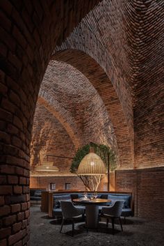 the interior of a restaurant with exposed brick walls and round tables, blue upholstered chairs