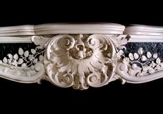 an intricately carved white and black mantle with floral designs on it's sides