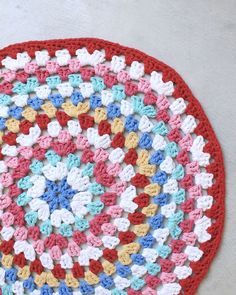 a crocheted doily is on the floor with white, red, and blue colors