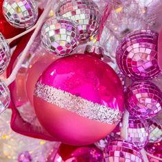 a pink christmas ornament surrounded by disco balls