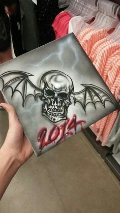 someone holding up a laptop with a skull and bat design on the cover in a store