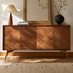 a large mirror sitting on top of a wooden dresser next to a lamp and vase