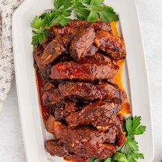 meat with sauce and parsley on a white platter, ready to be eaten