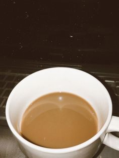 a white cup filled with liquid sitting on top of a counter next to an oven