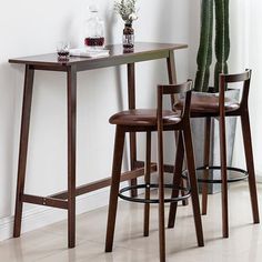 two stools and a table in front of a wall with a plant on it