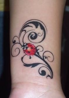 a ladybug tattoo on the wrist with swirls and curls around it's edges