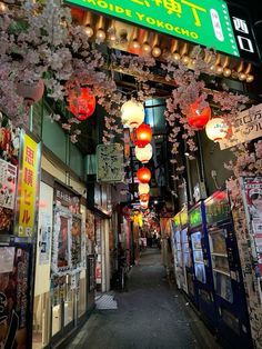 an alley way with lanterns hanging from it's ceiling and posters on the walls