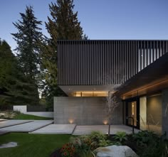 an exterior view of a modern house with landscaping in the foreground and trees on the other side