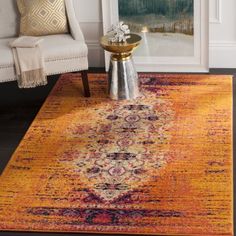 an orange and yellow area rug in a living room with a white chair next to it