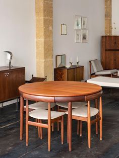 a table and chairs in a room with wood flooring, white walls and wooden furniture