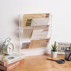 there is a desk with some books and an alarm clock next to it on the table