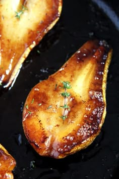 three pieces of food cooking in a skillet on a stove top with some seasoning