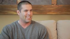 a man sitting on a couch smiling at the camera