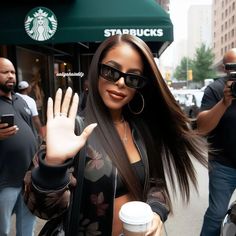 a woman with sunglasses on holding up her hand in front of a starbucks coffee shop