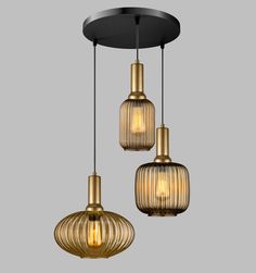 three pendant lights hanging from the ceiling in gold and black tones, one light is turned on