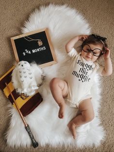 a baby wearing glasses laying on the floor next to a harry potter sign