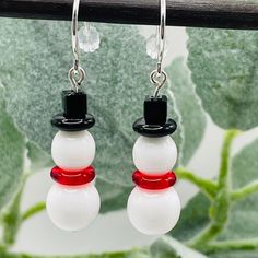 a pair of snowmen wearing black and white hats are hanging from silver earwires