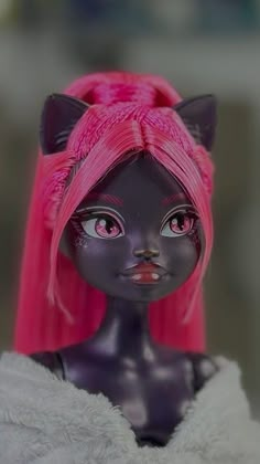 a black doll with pink hair and cat ears on it's head, wearing a white fur coat