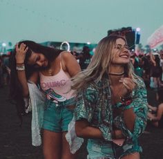 two young women are laughing and having fun at an outdoor music festival with emoticions surrounding them