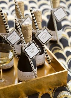 some wine bottles with black and white striped labels on them are sitting in a gold tray