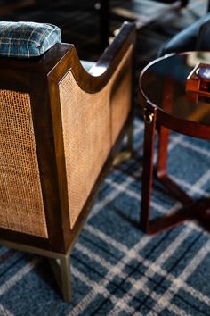 a chair and table in a room with plaid rugs on the floor next to each other