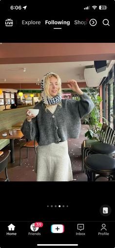 a woman is taking a selfie with her cell phone while wearing a sweater and scarf