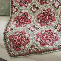 a crocheted blanket sitting on top of a couch next to a window sill