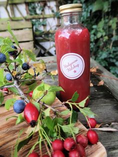 a glass jar filled with liquid sitting on top of a wooden table next to berries