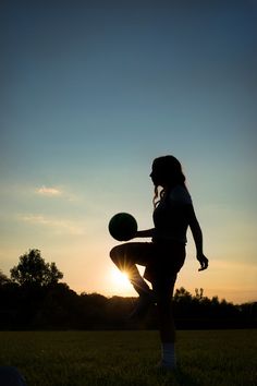 the silhouette of a woman holding a ball in her hand and stretching to catch it