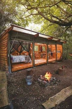 a small wooden cabin in the woods with a fire pit