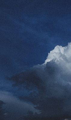 an airplane is flying in the sky with dark clouds behind it and blue skies above