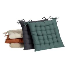 three pillows with ties hanging from them on a white background, one is green and the other two are brown