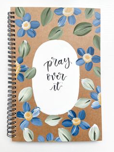 a brown notebook with blue flowers and the words pray over it