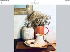 a table topped with a vase filled with flowers next to a white plate and cup