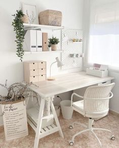 a white desk and chair in a room with shelves on the wall above it, next to a potted plant