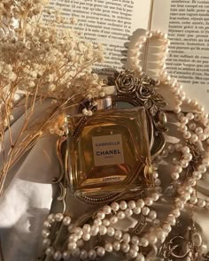 a bottle of chanel perfume sitting on top of a table next to pearls and flowers