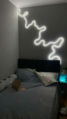 a bed room with a neatly made bed and a neon light on the wall above it