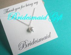 the bridesmaid gift card has a white pearl on it and is attached to a silver chain