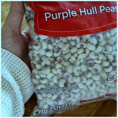 a person holding a bag of purple hull peas in their hand and it is white